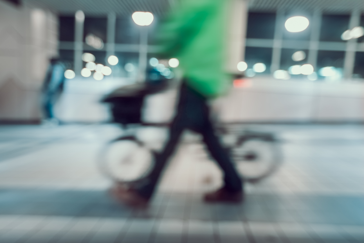 Imagen borrosa de hombre con camisa verde y bicicleta