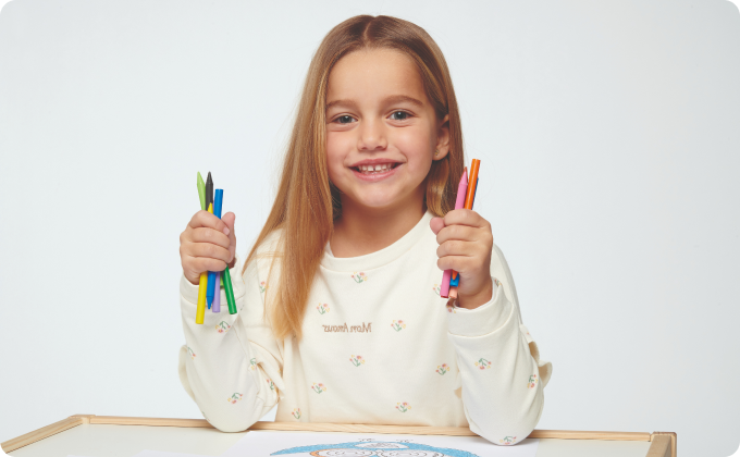 niña rubia sentada sujetando pinturas