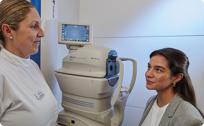 auxiliar y mujer joven con jersey gris durante una prueba oftalmológica