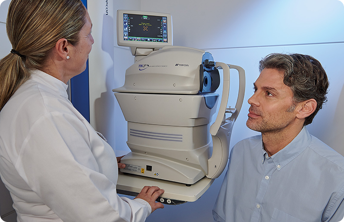 hombre maduro y auxiliar durante una topografía corneal