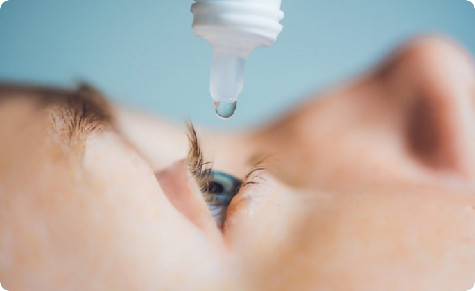 primer plano ojo azul mientras se instila un colirio