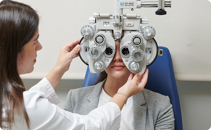 médico y paciente joven con jersey azul junto a un foróptero