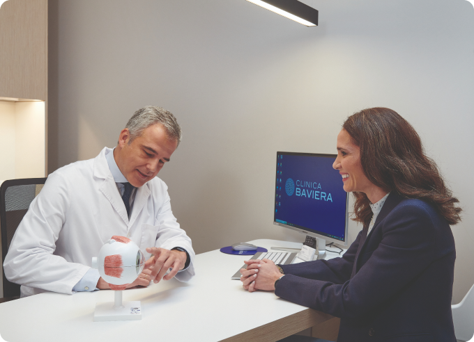 oftalmólogo explicándole las partes del ojo a mujer joven en consulta