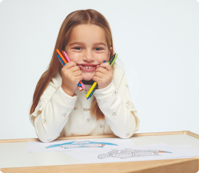 niña rubia sentada sujetando pinturas
