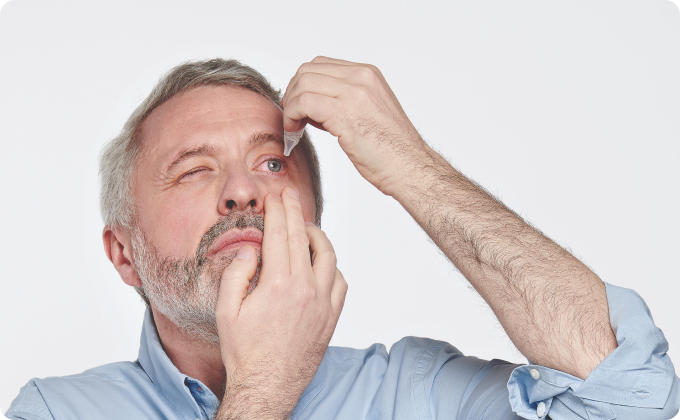 hombre canoso instilándose un colirio