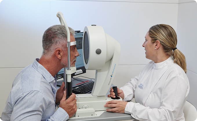 hombre maduro y auxiliar durante una topografía corneal