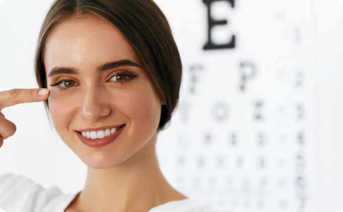 mujer morena joven con el pelo recogido señalándose un ojo frente a un optotipo