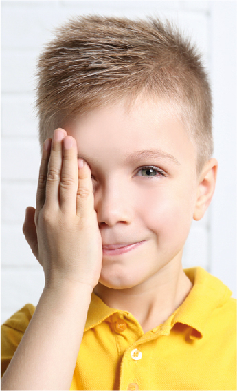 Nio rubio con polo amarillo se tapa un ojo