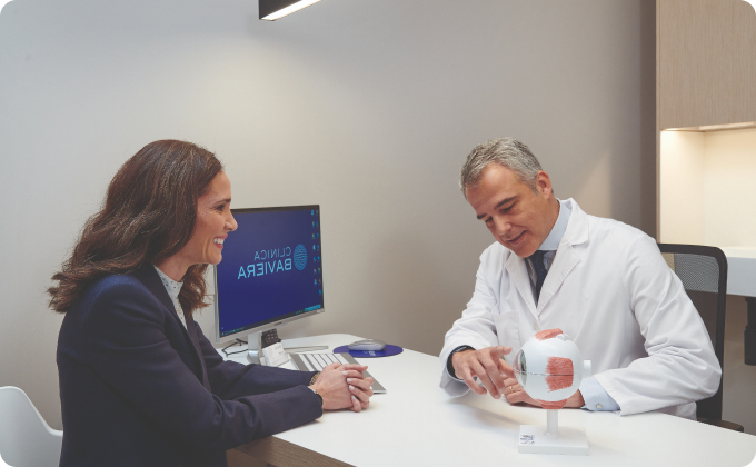 oftalmólogo señala un ojo a una paciente durante la consulta