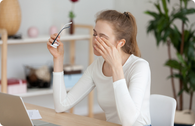 mujer joven se quita las gafas y se frota los ojos